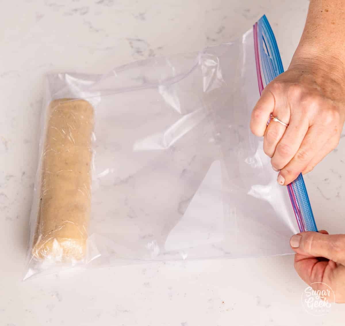 hands placing wrapped marzipan in a Ziploc bag. 