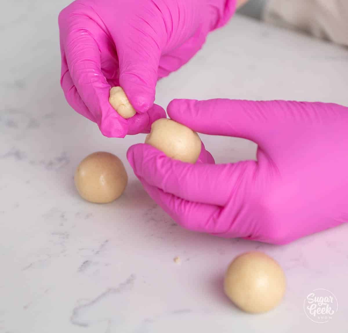 hands sectioning marzipan into balls for making decorations. 