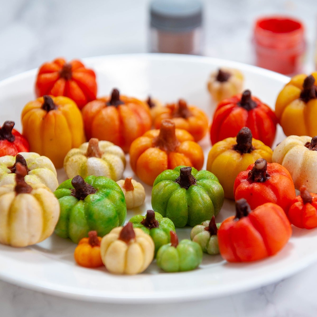 close up of marzipan candy pumpkins on a white plate
