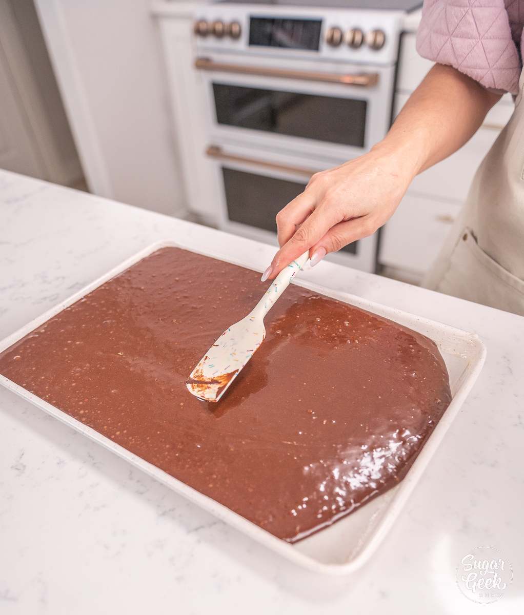 hand smoothing out cake batter using a spatula