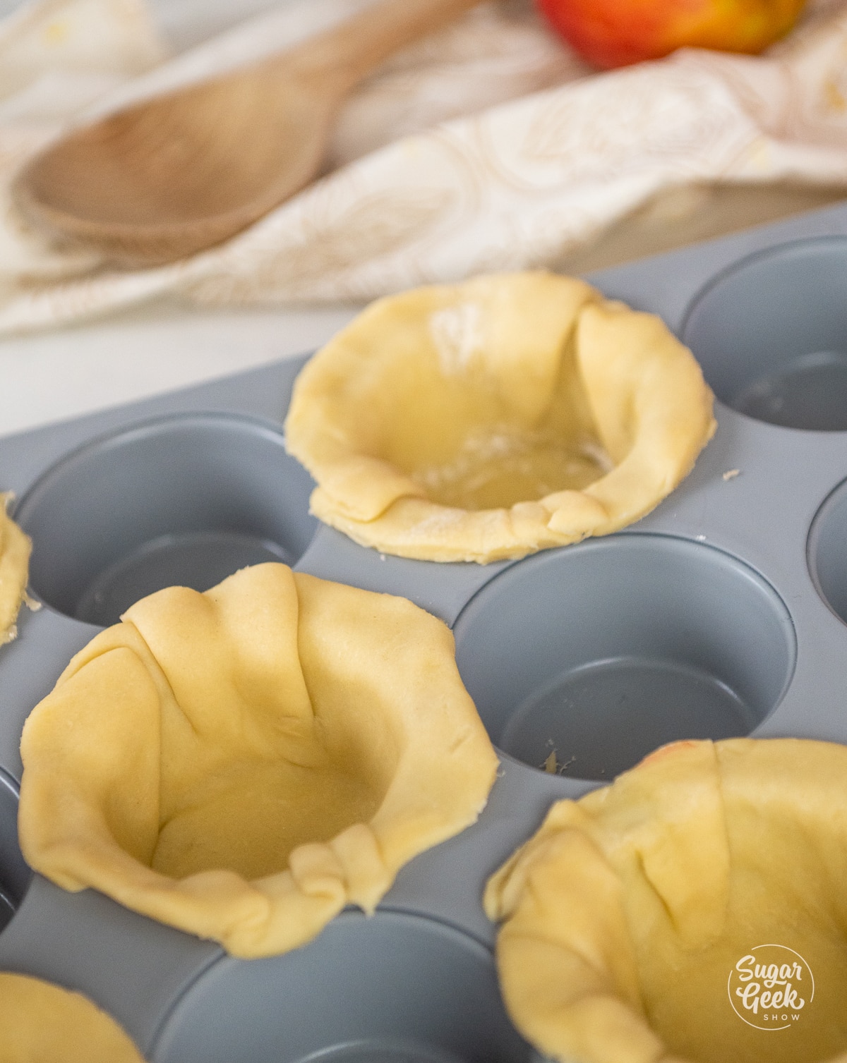 picture of muffin tin with pie dough pressed into every other cup.
