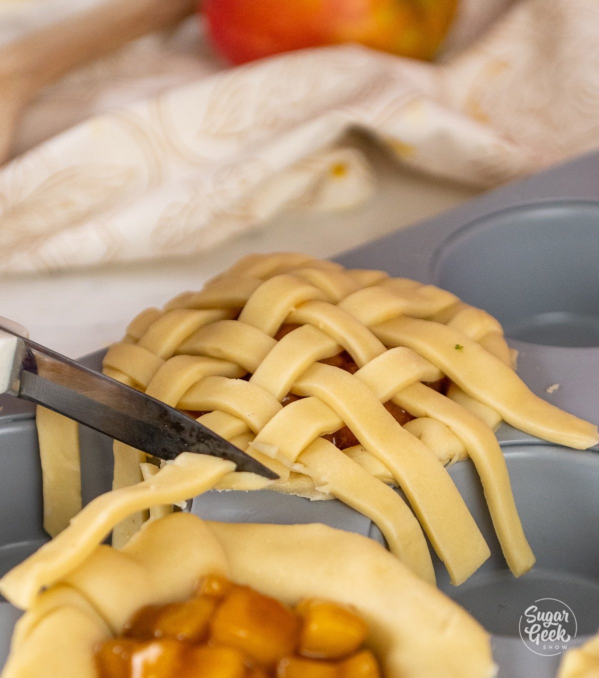 cutting off the excess dough from creating a lattice top on the mini pie