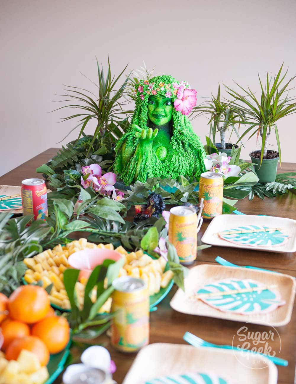 table decorated with luau themed decorations and moana tifiti birthday cake