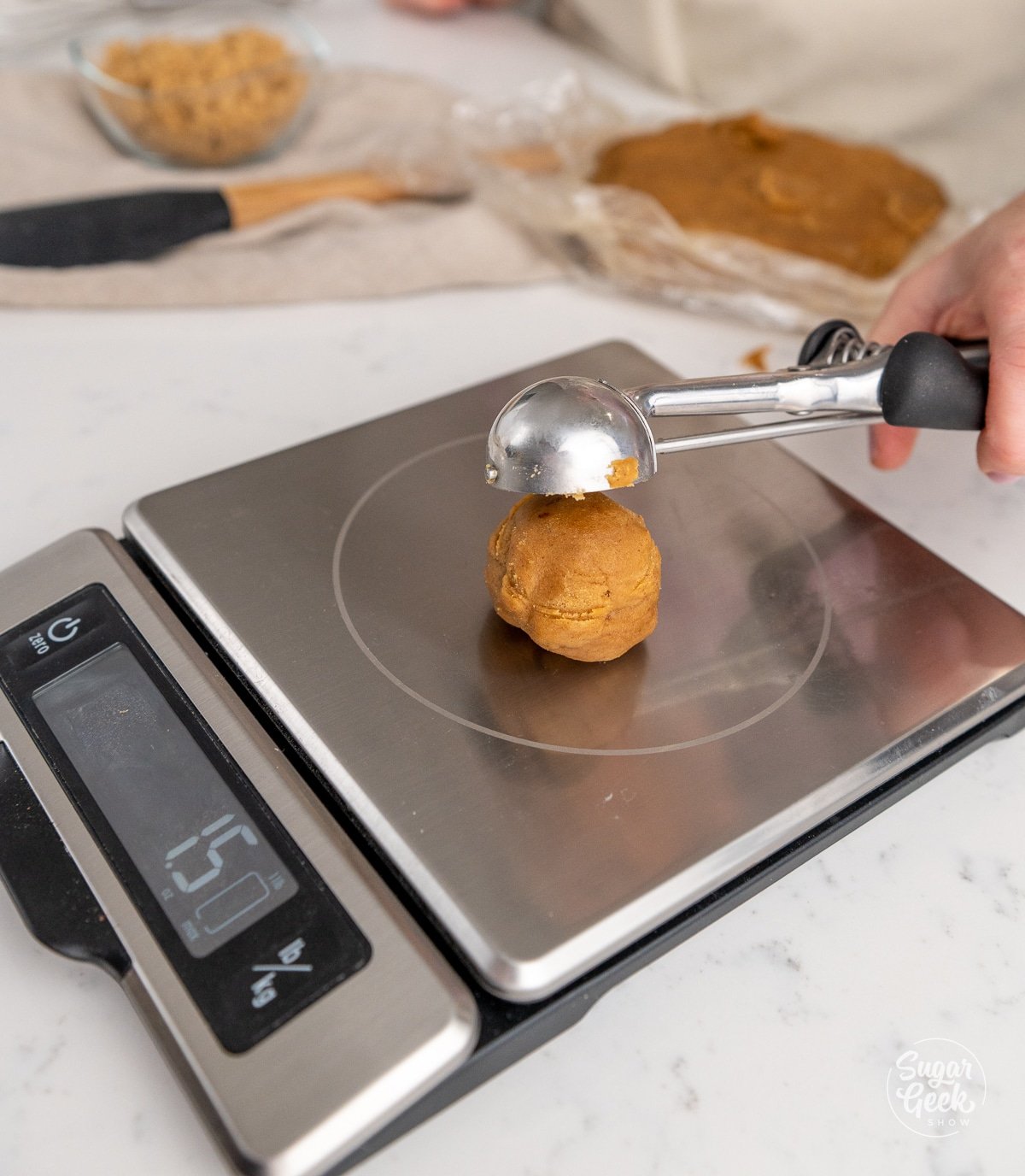 cookie scoop placing a dough ball on a food scale