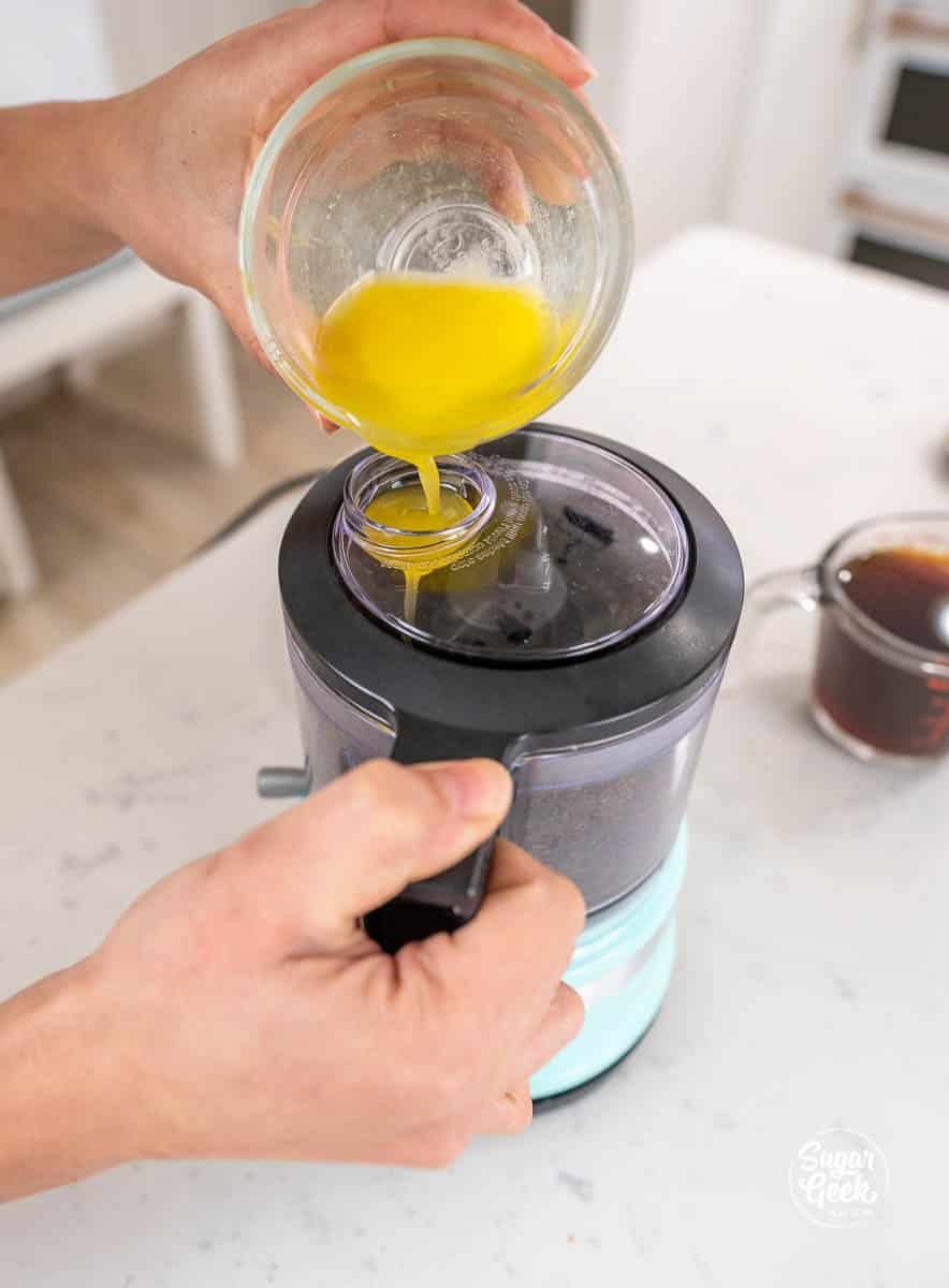 pouring melted butter into a food processor of oreos