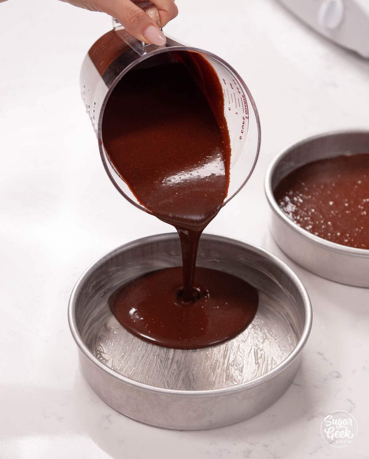 pouring chocolate batter into cake pans
