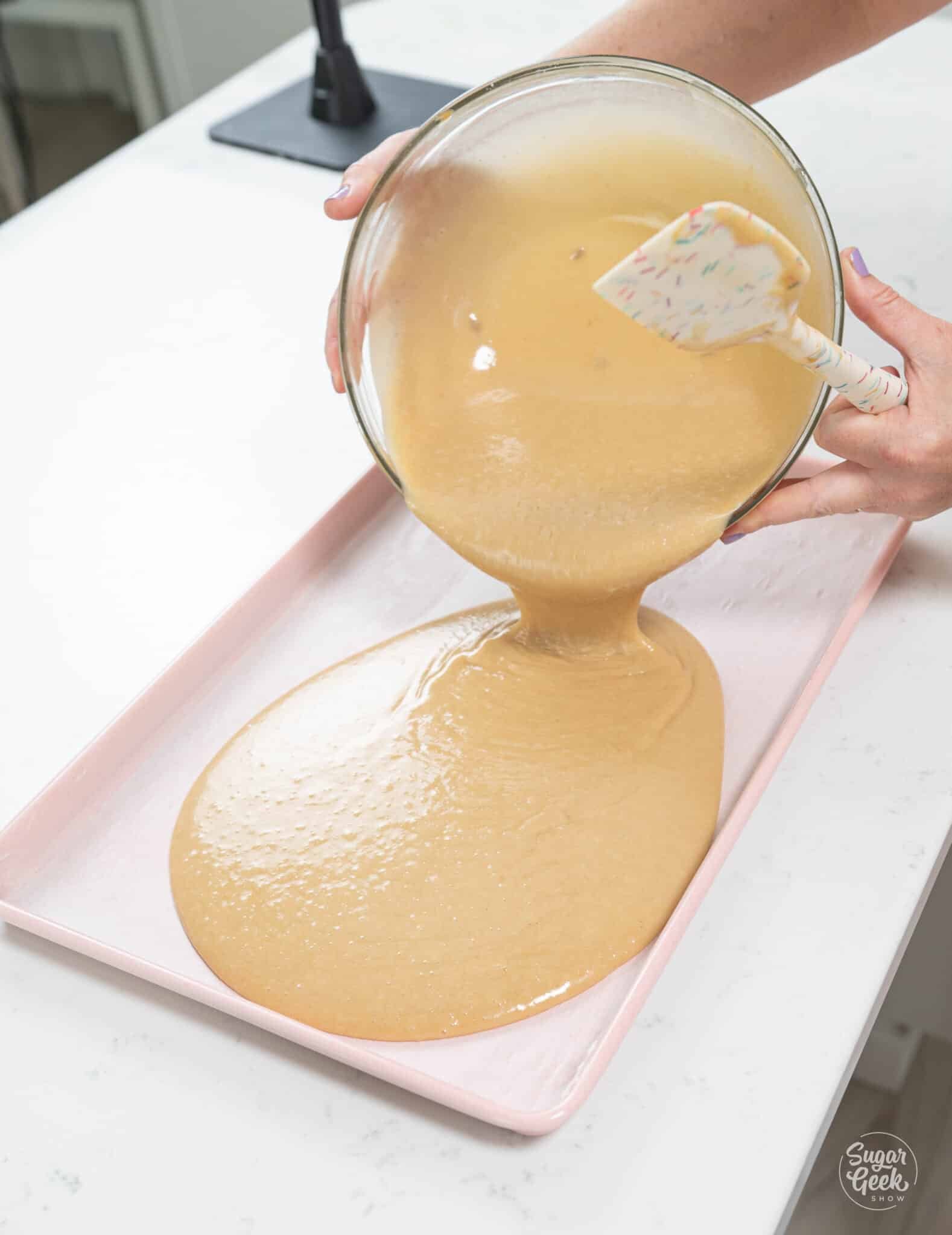 hand pouring bowl of batter into sheet pan.