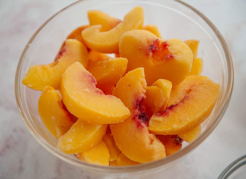 bowl of frozen peaches in clear glass bowl