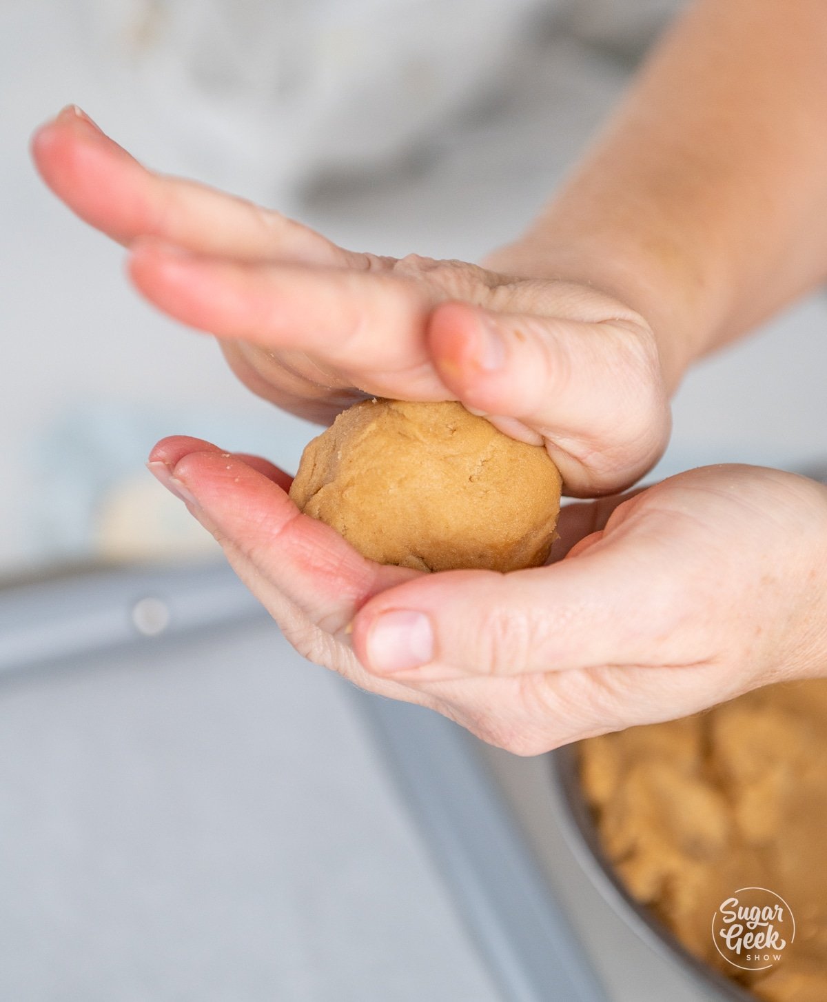 hands rolling peanut butter dough into a ball