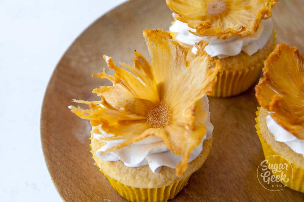dried pineapple flowers on cupcake on wooden plate