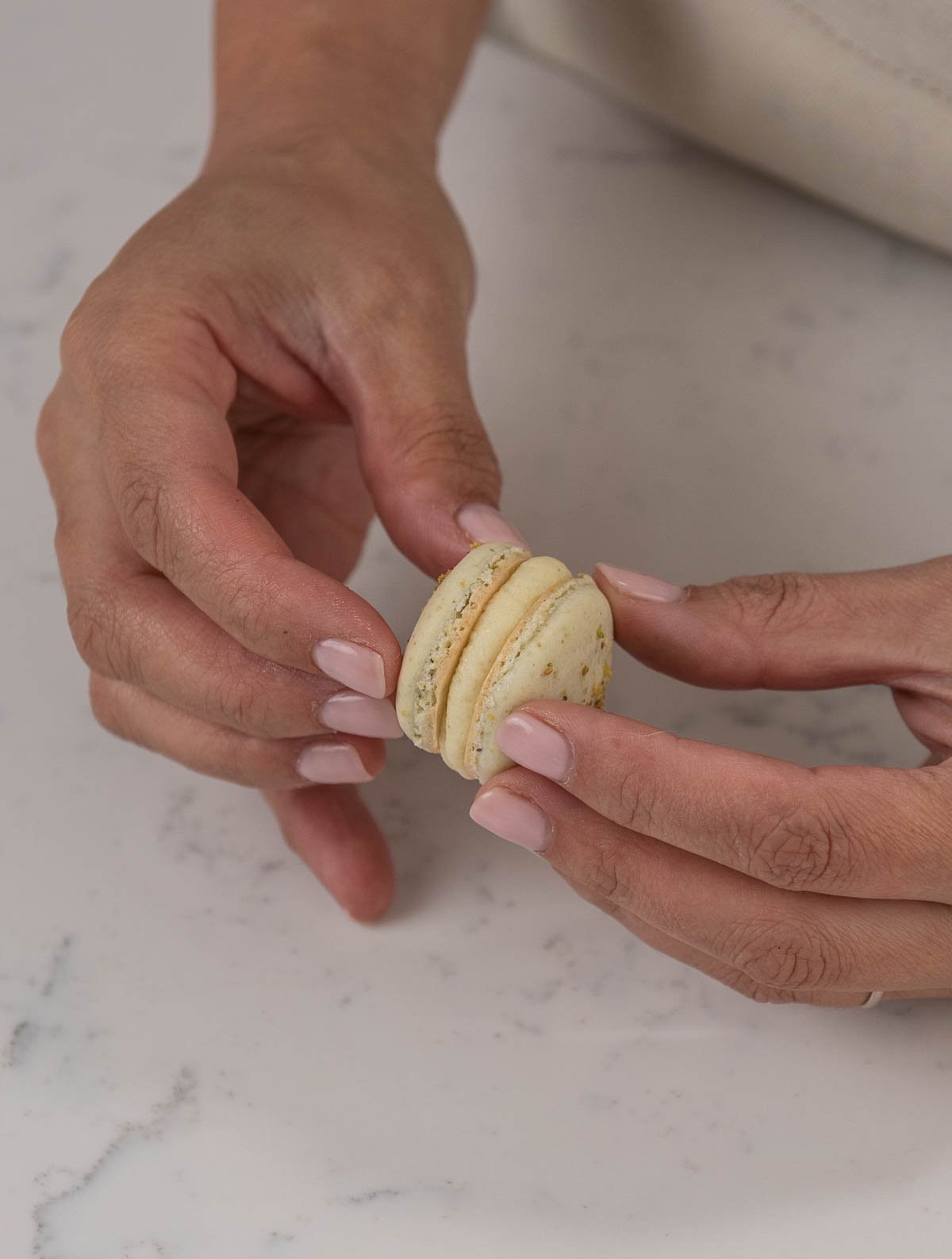 hands assembling a pistachio macaron