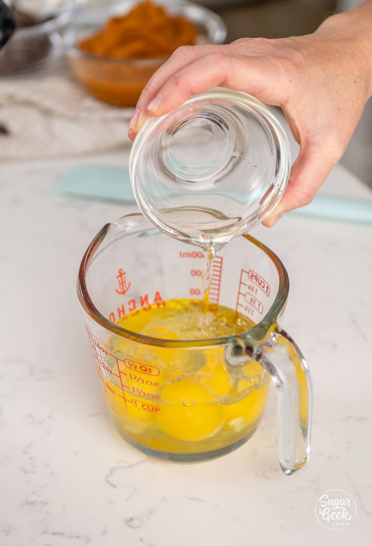 hand pouring a small bowl into a measuring cup of eggs