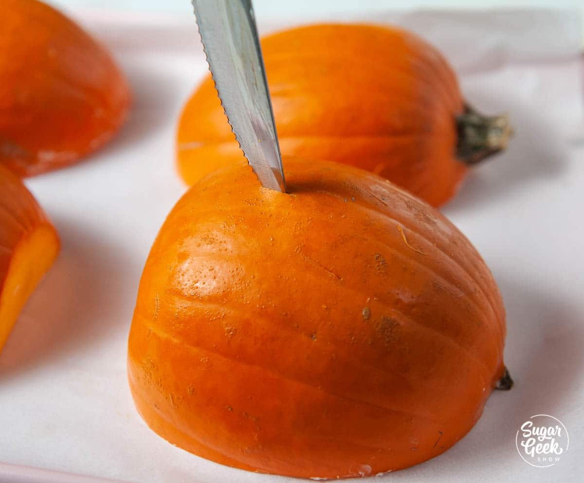 knife piercing the skin of a cut pumpkin