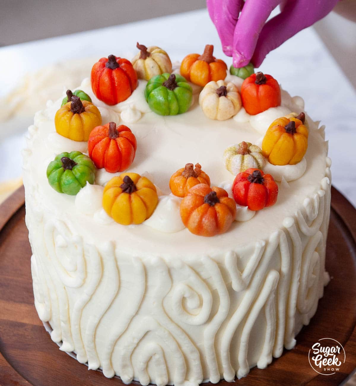 adding marzipan candy pumpkins to the top of the cake
