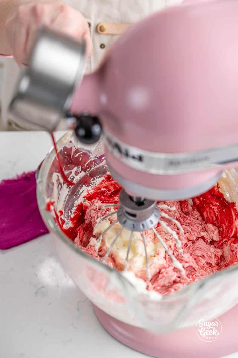 adding raspberry filling to a bowl of buttercream