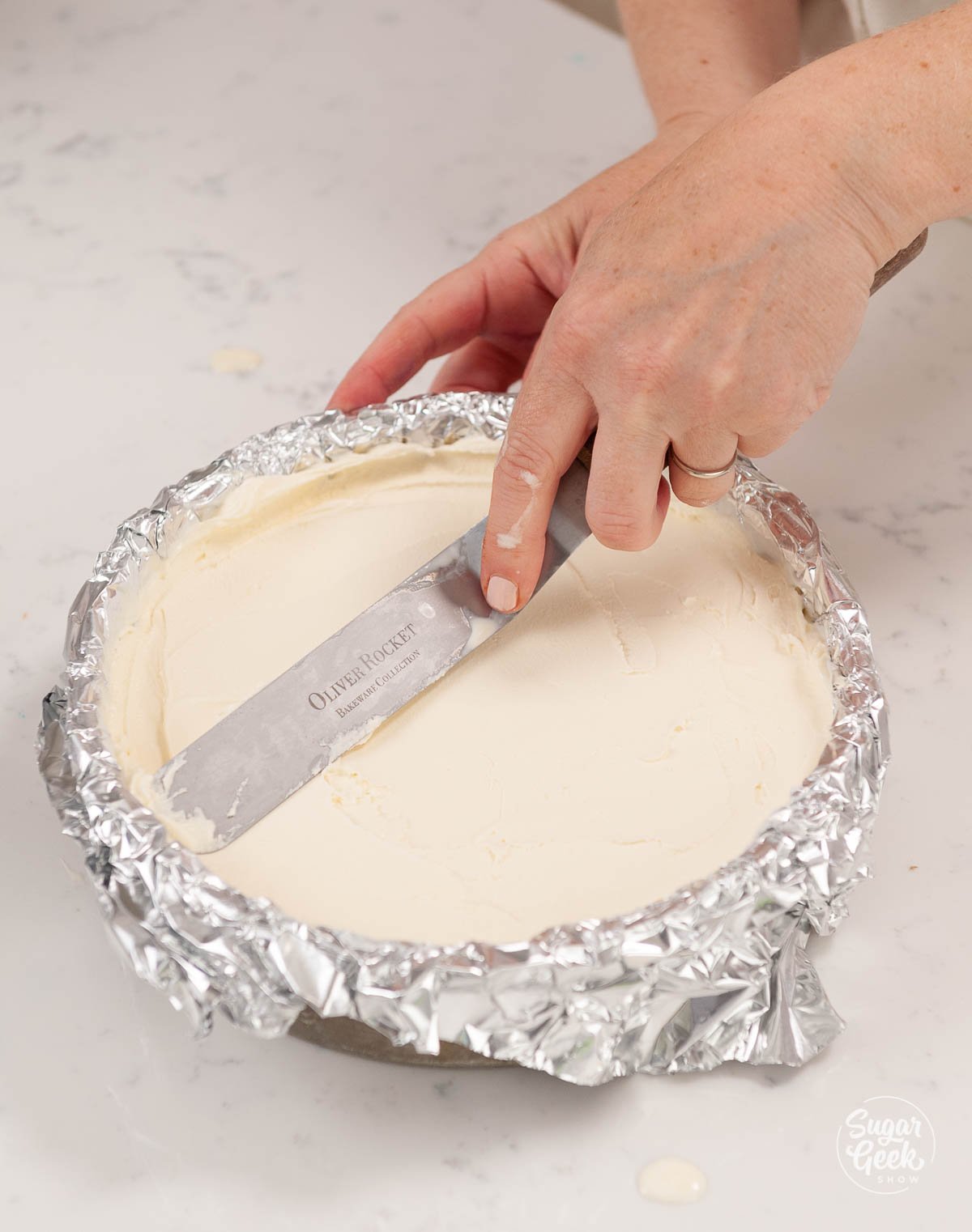 smoothing ice cream in an aluminum foil lined cake pan