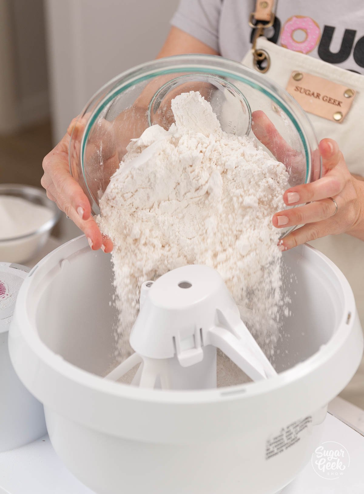 bowl pouring flour into a stand mixer mixing bowl