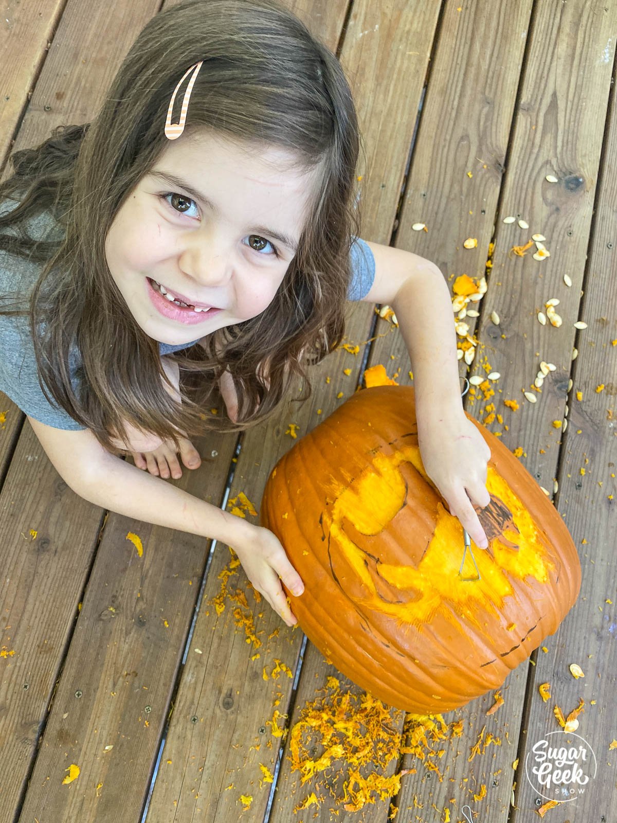 girl looking up from carved pumpkin