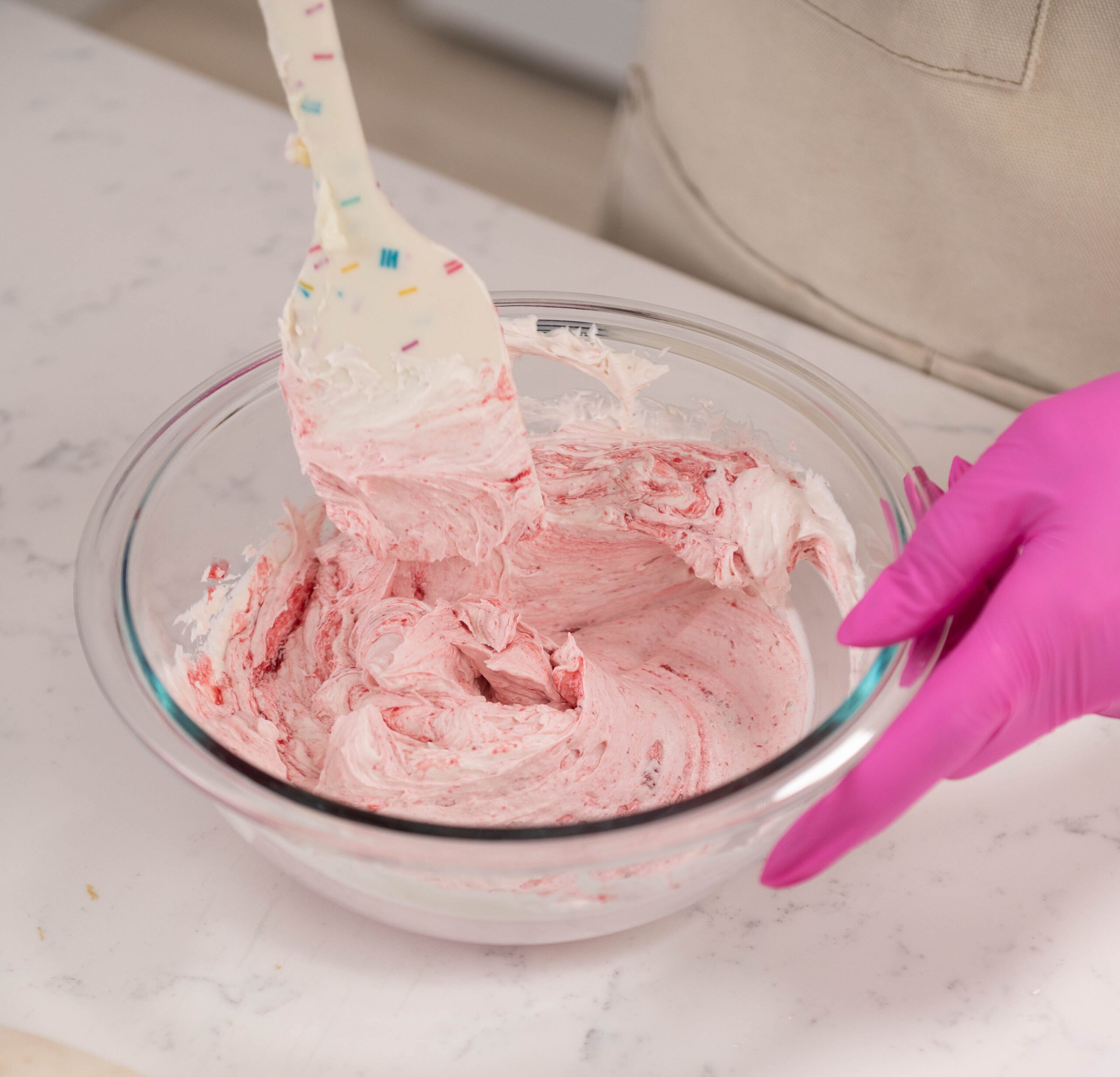 hand holding spatula mixing bowl of buttercream
