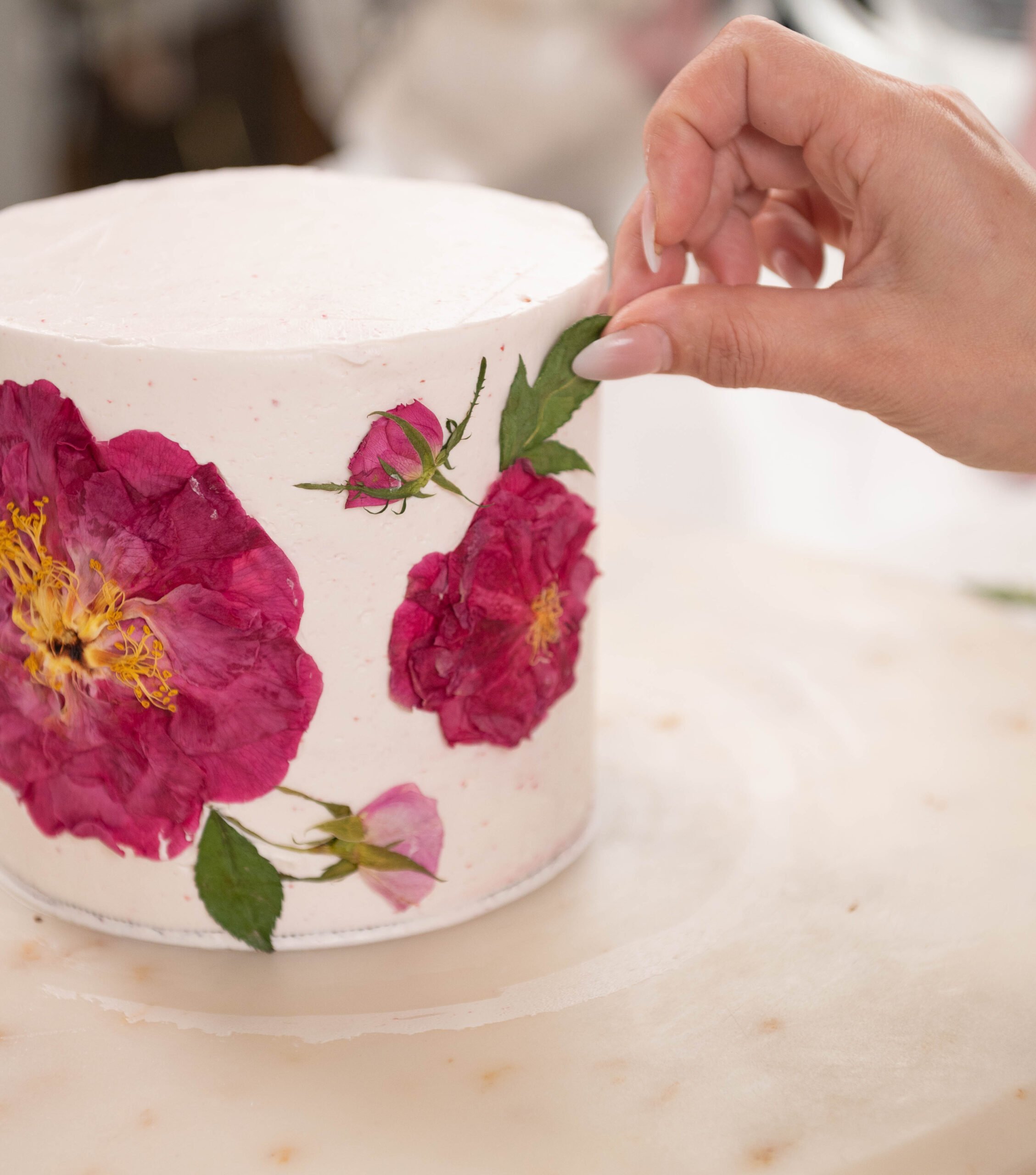 hand placing flowers on to cake