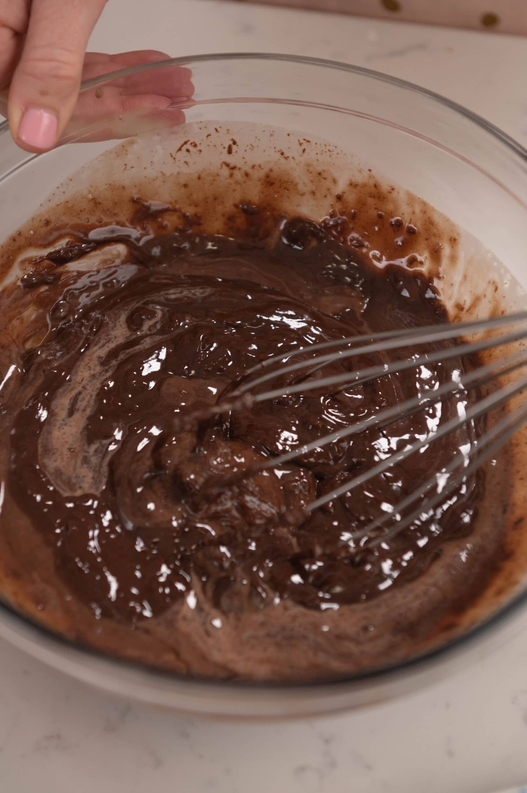 close up of ganache in a glass bowl with a whisk