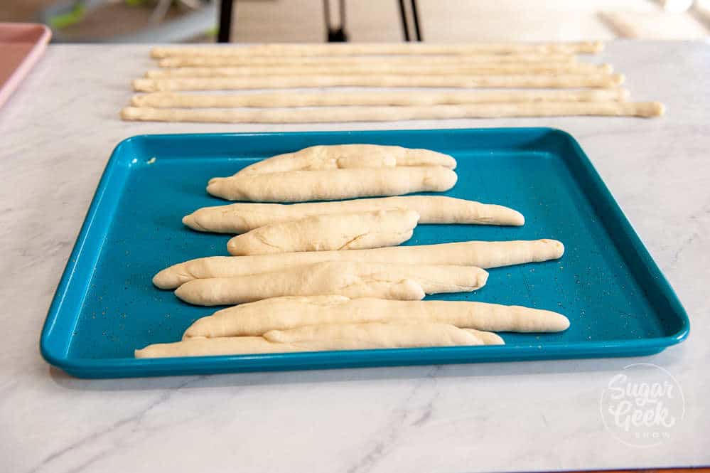 shaping pretzel dough by rolling into long skinny snakes