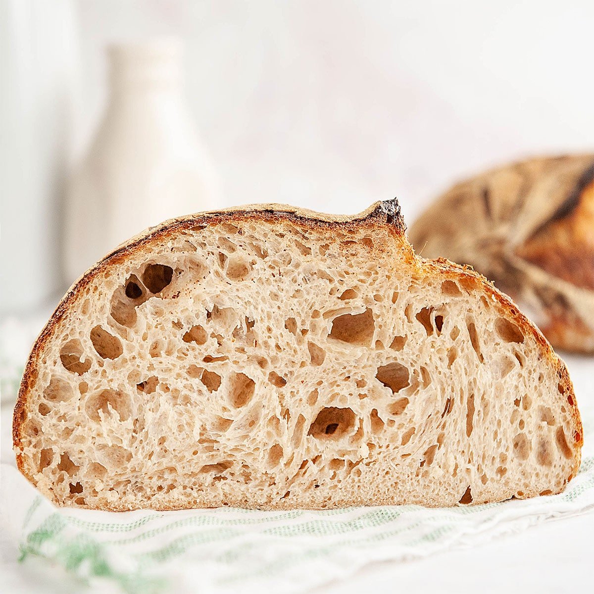 loaf of sourdough bread cut in half on white background