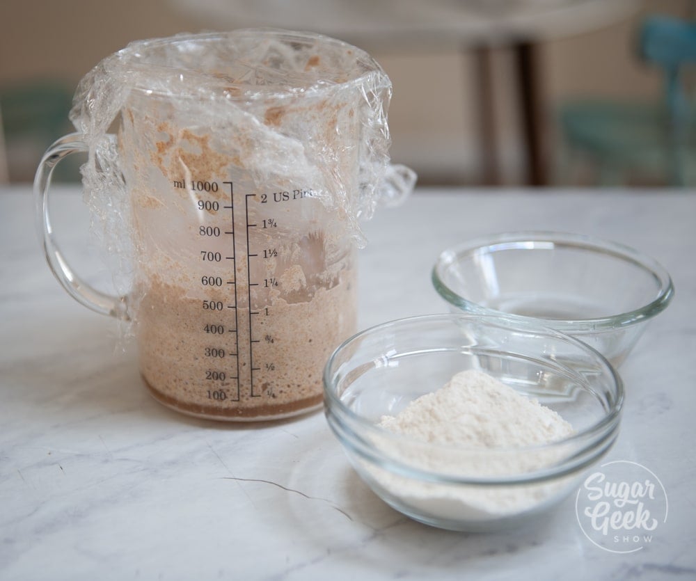 container of sourdough starter, clear bowl of flour and clear bowl of water