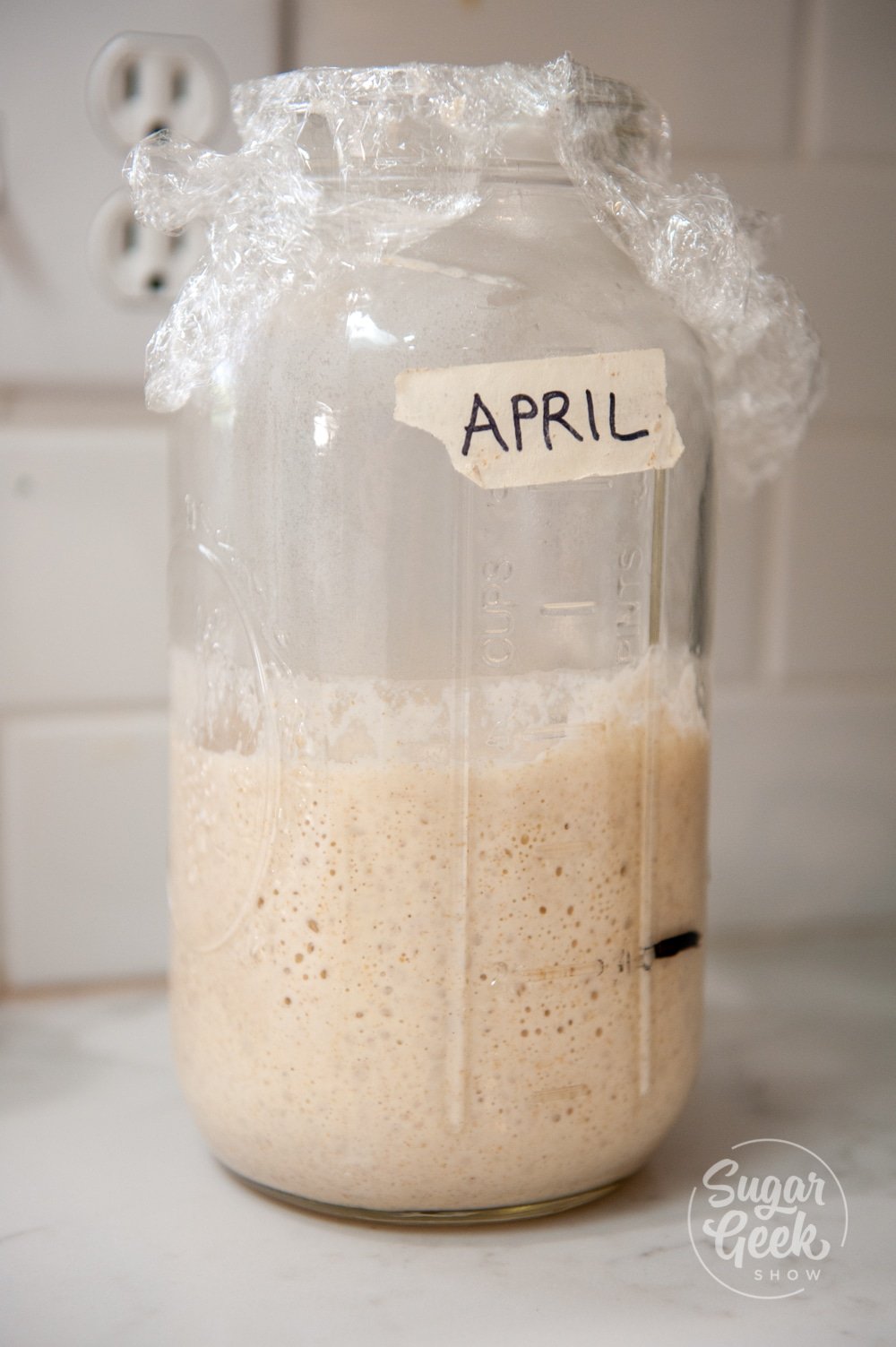 sourdough starter in clear jar labeled april