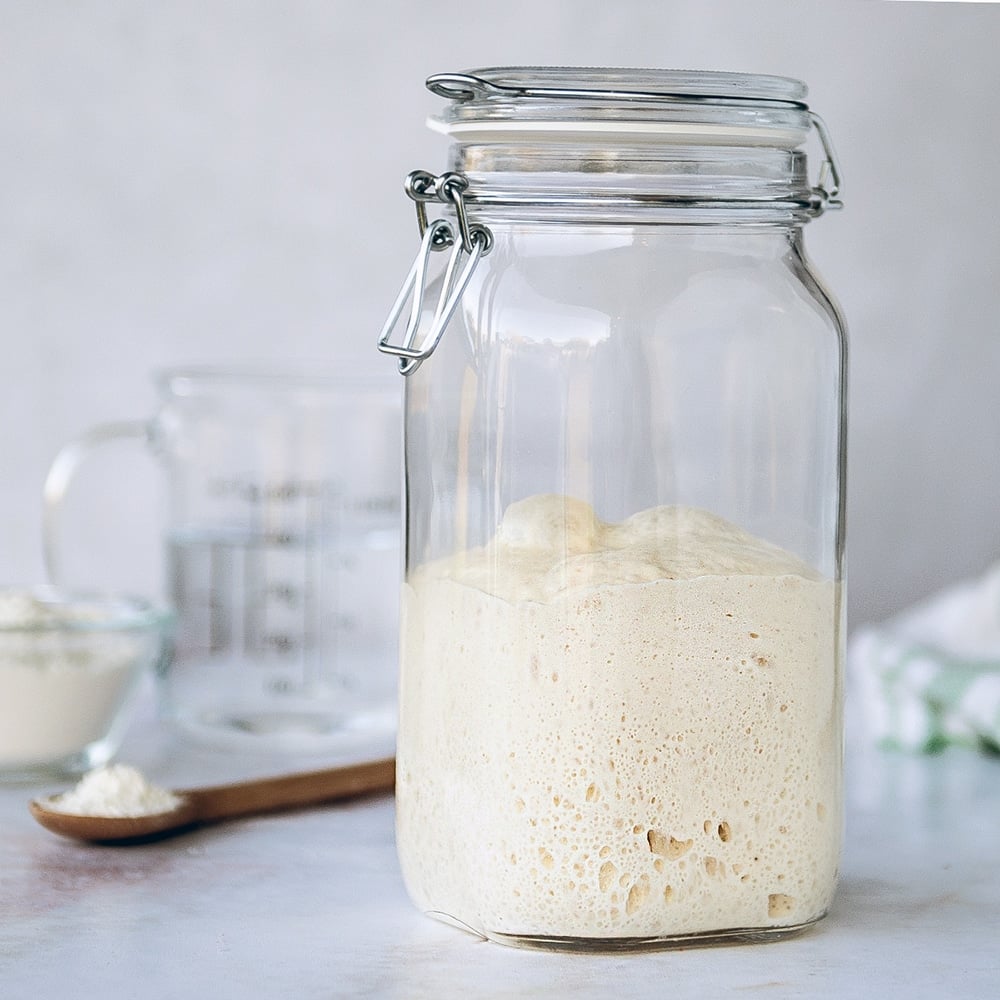 sourdough starter in clear jar on white background