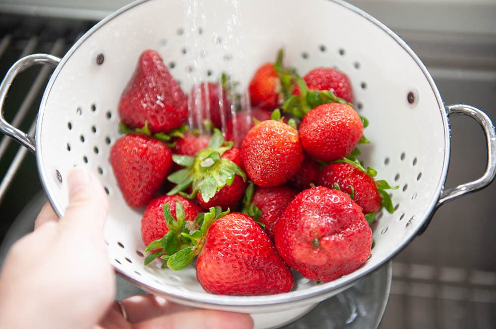 strawberries rinsed in water in white colander