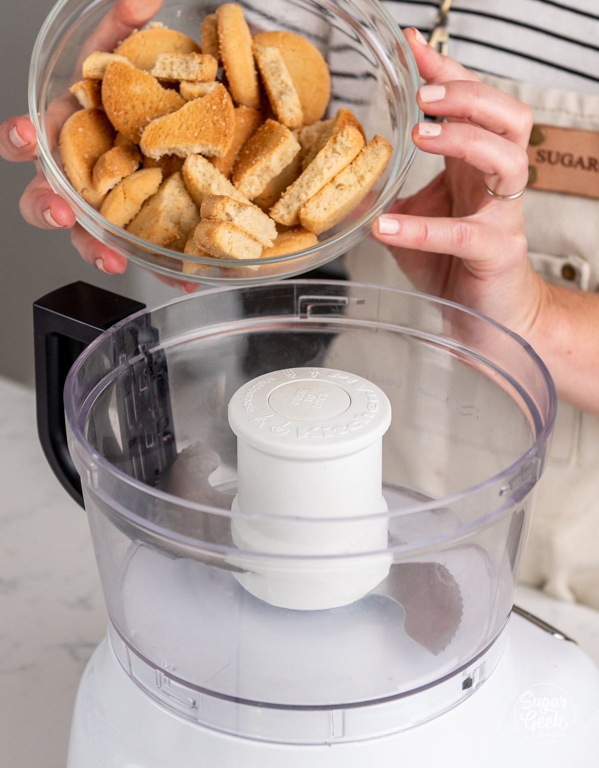 hands adding shortbread cookies to a food processor.