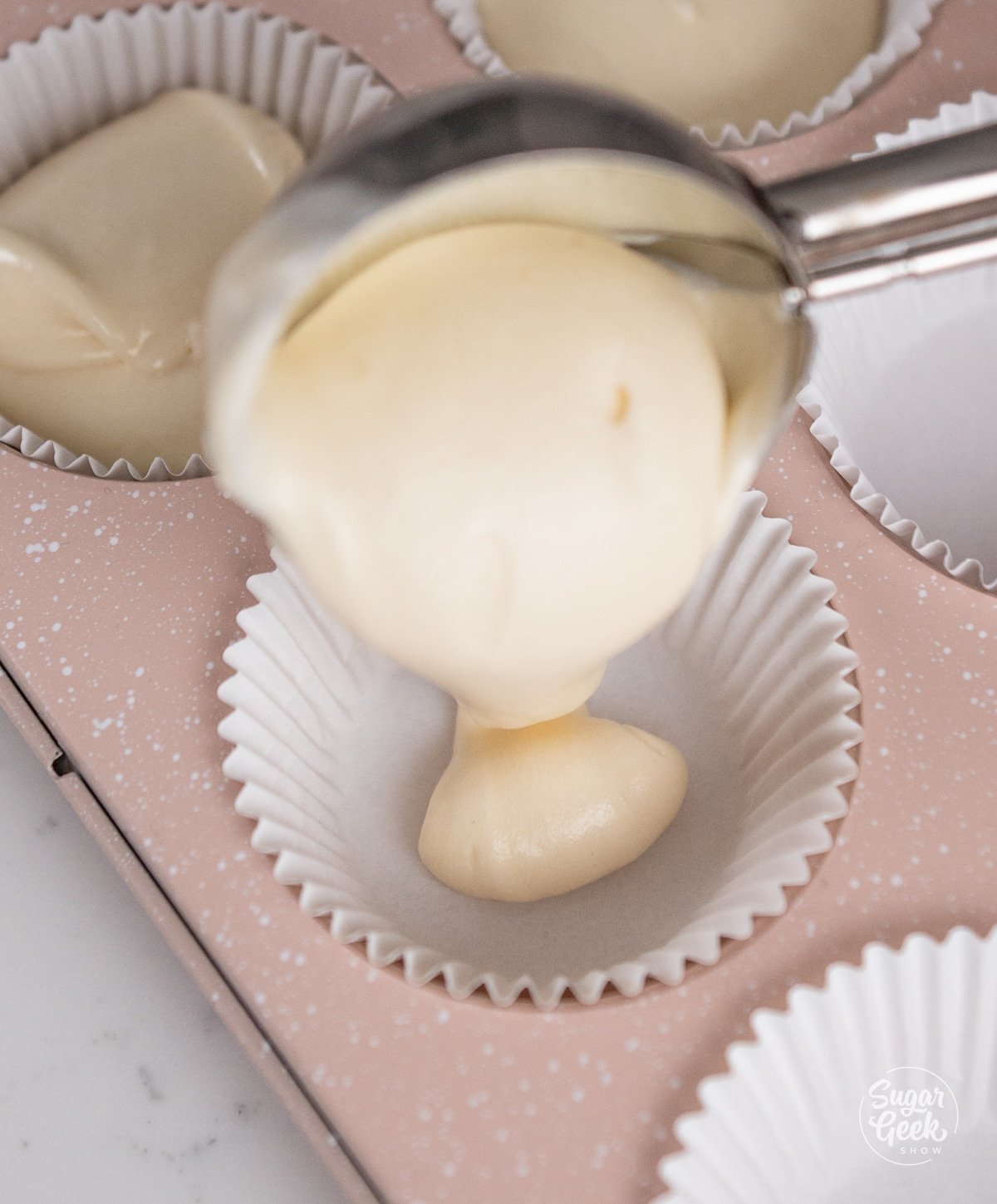 a cupcake scoop pouring batter into a cupcake liner.