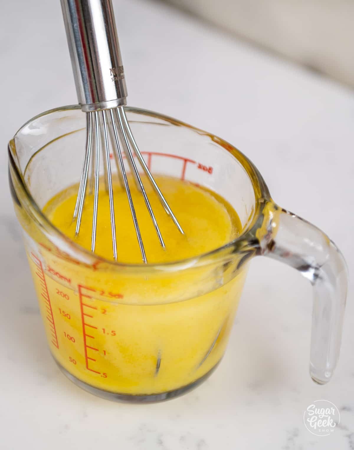 whisking eggs and oil together in a measuring cup.