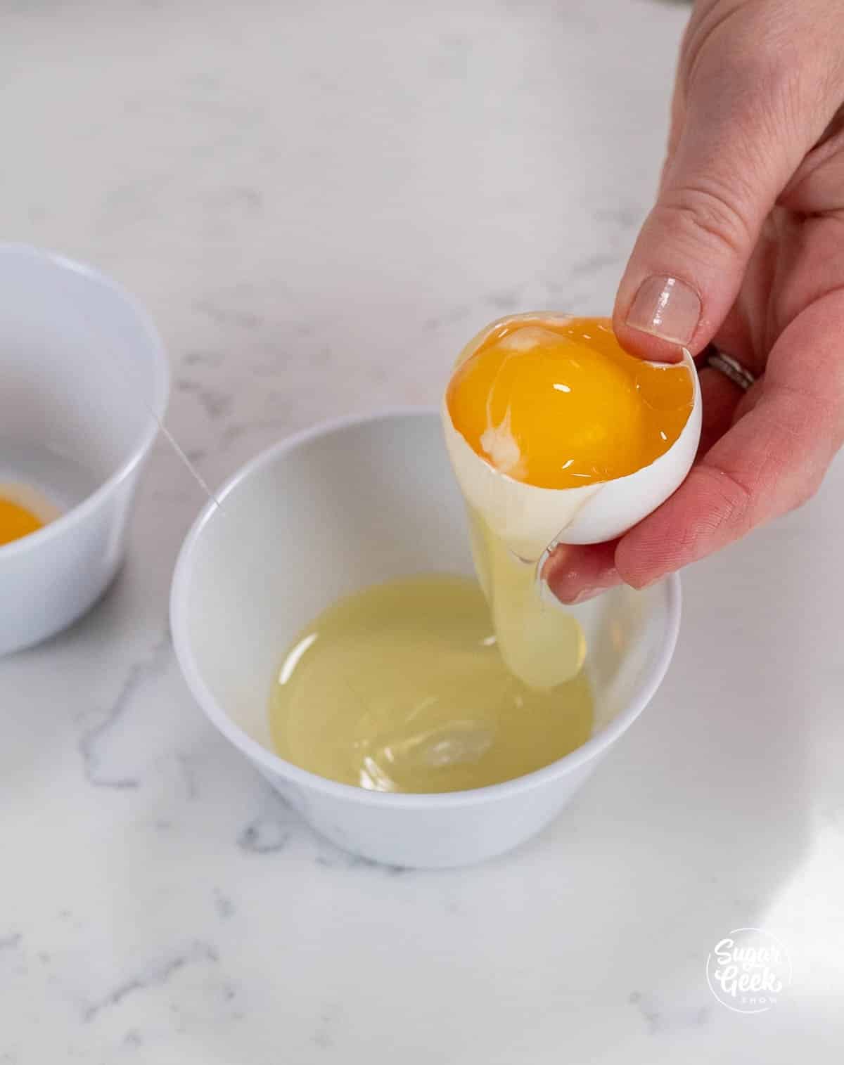 hand separating egg yolks and white