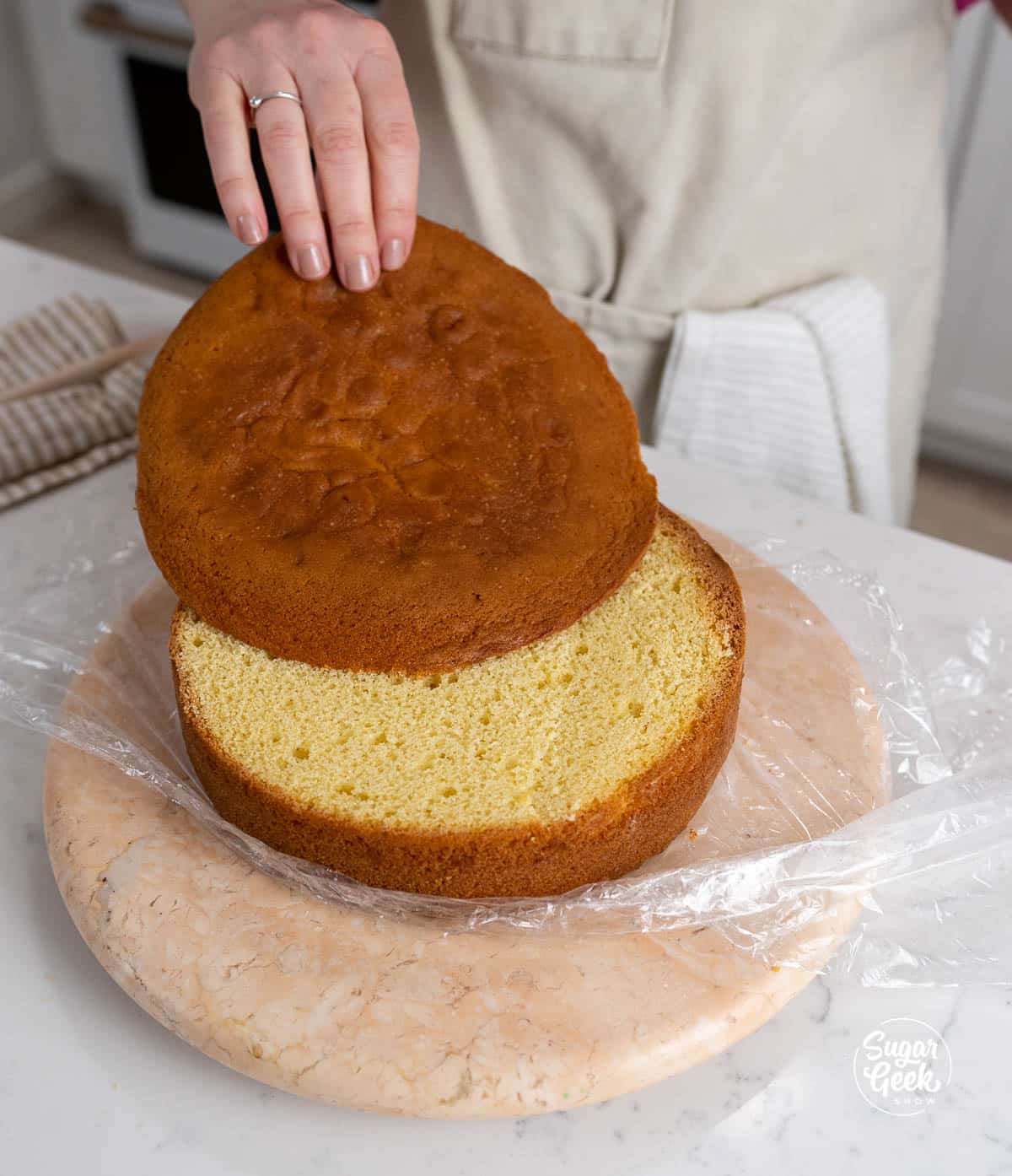 hand removing the dome from the top of a yellow cake