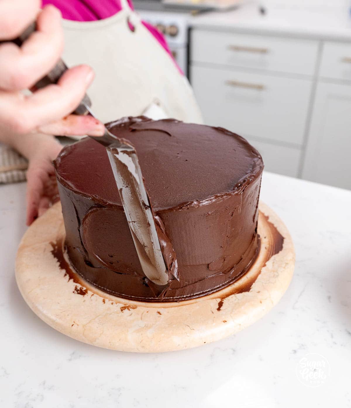 spreading chocolate frosting onto the outsides of a cake